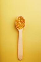 Vitamin D3 Capsules in a spoon with other vitamin D3 capsules around them on a yellow background photo