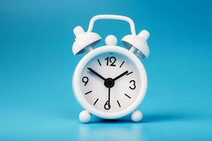 White retro alarm clock on blue background. Concept of time with free space for text. photo