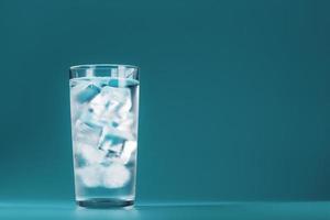 Ice cubes in a glass with crystal clear water on a blue background. photo