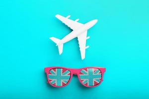 Pink glasses with the flag of the United Kingdom in lenses on a blue background with a white airplane. photo