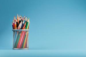 Colorful pencils in a metal jar on a blue background. photo