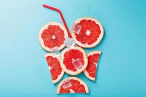 A composition of grapefruit slices and ice cubes with a blue background in the form of a refreshing drink photo