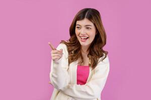 Portrait of happy cheerful young woman pointing to empty copy space for product over isolated pink background photo