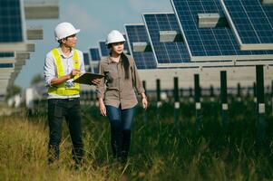 joven inspector asiático ingeniero hombre y mujer caminando comprobando la operación en una granja solar foto