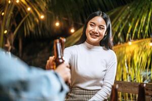 Portrait of Happy Asian friends having dinner party together - Young people toasting beer glasses dinner outdoor  - People, food, drink lifestyle, new year celebration concept. photo