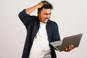 Portrait of anger asian businessman working on laptop computer isolated over white background