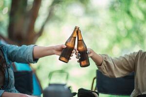 mujeres jóvenes animan y beben bebidas frente a la tienda de campaña foto