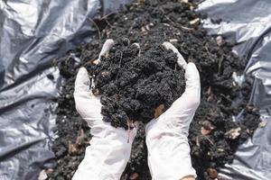 Hands holding abundance soil for agriculture or preparing to plant  Testing soil samples on hands with soil ground background. Dirt quality and farming concept. Selective focus on black soil in front photo