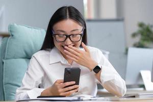 Asian business woman reading funny and funny messages and news from phone photo