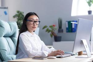 retrato de un joven hermosa asiático mujer en el oficina. mujer de negocios, director, persona de libre dedicación foto