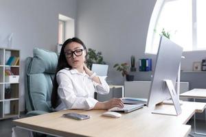 Overtired Asian woman office worker, has severe neck pain photo