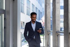 joven y exitoso hombre de negocios afroamericano confiado moviéndose con el celular en las manos foto