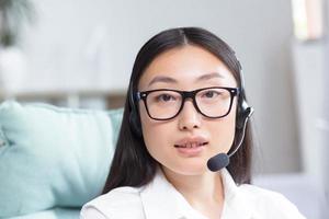 cerca arriba foto. retrato de un joven hermosa asiático mujer en auriculares con un micrófono. foto