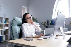 Overtired Asian woman office worker, has severe neck pain photo