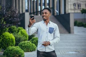 Young african american freelancer talking on video call near office cheerful smiling man photo