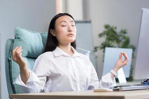 Asian business woman working in the office, resting and meditating photo