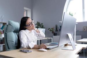 Overtired Asian woman office worker, has severe neck pain photo