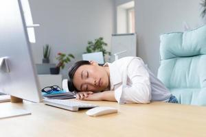 Young Asian businesswoman fell asleep at the desk on her hands in the office, tired, routine photo