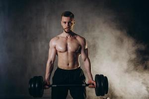 masculino rubio atleta ascensores pesas con mano en bíceps estudio foto con gotas de lluvia