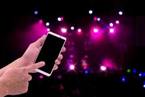 Hands holding mobile smartphone with light bokeh in concert blur background photo