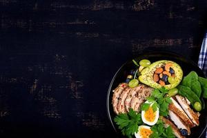 Ketogenic diet. Buddha bowl dish with meatloaf, chicken meat, avocado, berries and nuts. Detox and healthy concept. Keto food. Overhead, top view, flat lay photo