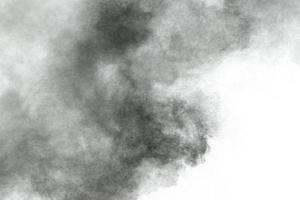 Black particles splattered on white background. Black powder dust splashing. photo