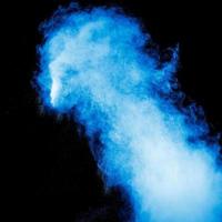 Blue dust explosion on black background. Freeze motion of color powder splash. photo