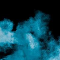 Blue dust explosion on black background. Freeze motion of color powder splash. photo