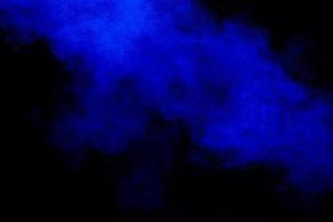 Blue dust explosion on black background. Freeze motion of color powder splash. photo
