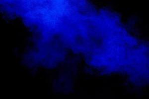 Blue dust explosion on black background. Freeze motion of color powder splash. photo