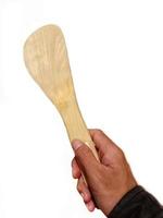 Hand with wooden kitchen spatula, cooking utesil. Isolated on white background photo