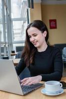 Beautiful businesswoman working on laptop in coffee shop. Female freelancer connecting to internet via computer. Blogger or journalist writing new article. photo