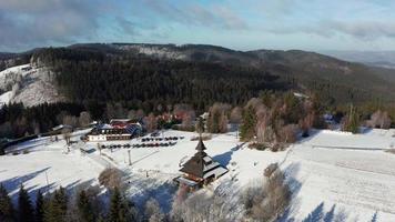 aéreo órbita Visão do uma Nevado campanário e chalé dentro beskydy montanha video