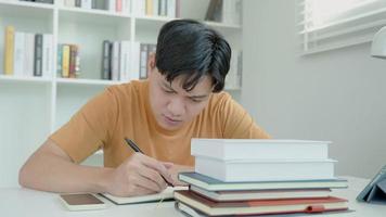 el estudiante asiático tiene ansiedad debido a los exámenes, los hombres se preparan para el examen y aprenden lecciones en la biblioteca. estrés, desesperación, prisa, malentendido lectura, desanimado, expectativa, conocimiento, cansado video