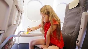 adorable peu fille en voyageant par avion séance par avion la fenêtre. enfant dessin image avec coloré des crayons. video