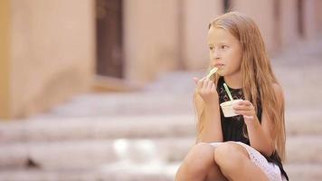 adorabile poco ragazza mangiare gelato all'aperto a estate. carino ragazzo godendo vero italiano gelato nel Roma video