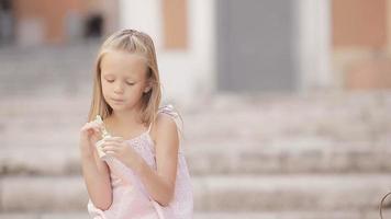 Adorable little girl eating ice-cream outdoors at summer. Cute kid enjoying real italian gelato in Rome video