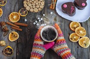 cup of black hot coffee in her hands, wearing colorful winter gloves on hands photo