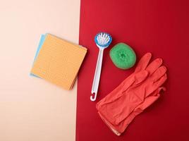 items for home cleaning red rubber gloves, brush, multi-colored sponges photo