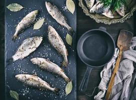 river fish on a black board and a black cast-iron frying pan photo