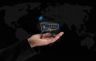 man's hand holds a miniature shopping cart on a dark background, concept of the start of world sales photo