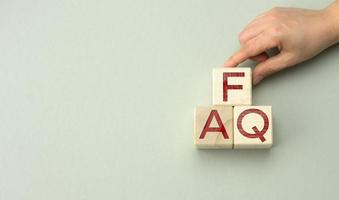 inscription FAQ frequently asked questions on wooden blocks on a gray background. QA concept, help and tips photo