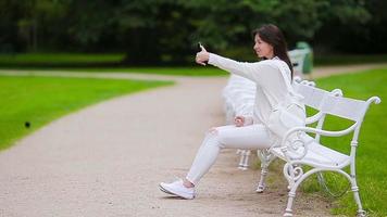 retrato de una mujer hermosa usando un teléfono inteligente al aire libre. video