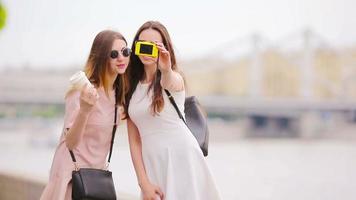 Kaukasisch meisjes maken selfie achtergrond groot brug. jong toerist vrienden op reis Aan vakantie buitenshuis glimlachen gelukkig. video