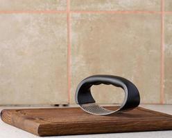 Hand held metal garlic press on a wooden cutting board photo