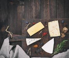 piezas de diferente quesos en un marrón de madera tablero queso Brie, roquefort, queso con nueces foto