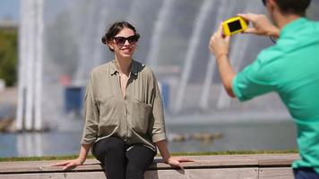 joven turista Pareja de viaje en Días festivos en Europa sonriente contento. caucásico amigos tomando selfie en parque antecedentes grande fuente video