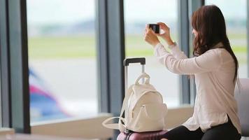 CIA aérea passageiro dentro a aeroporto salão esperando para voar aeronave e levando foto do aeródromo. caucasiano mulher com Smartphone dentro a esperando quarto video