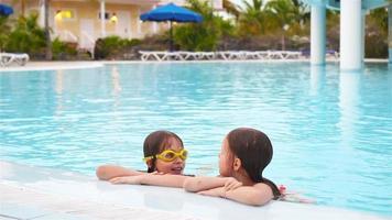adorable pequeño muchachas jugando en al aire libre nadando piscina juntos video