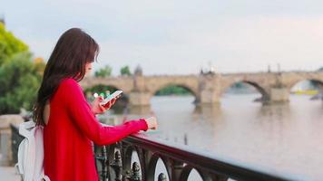 jung kaukasisch Frau mit ihr Smartphone draussen Hintergrund berühmt Brücke. video